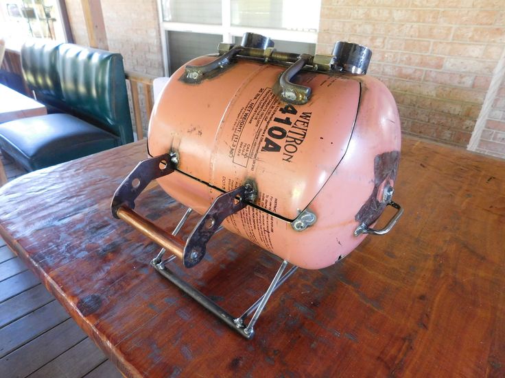 an old style propane tank sitting on a wooden table in a room with leather chairs