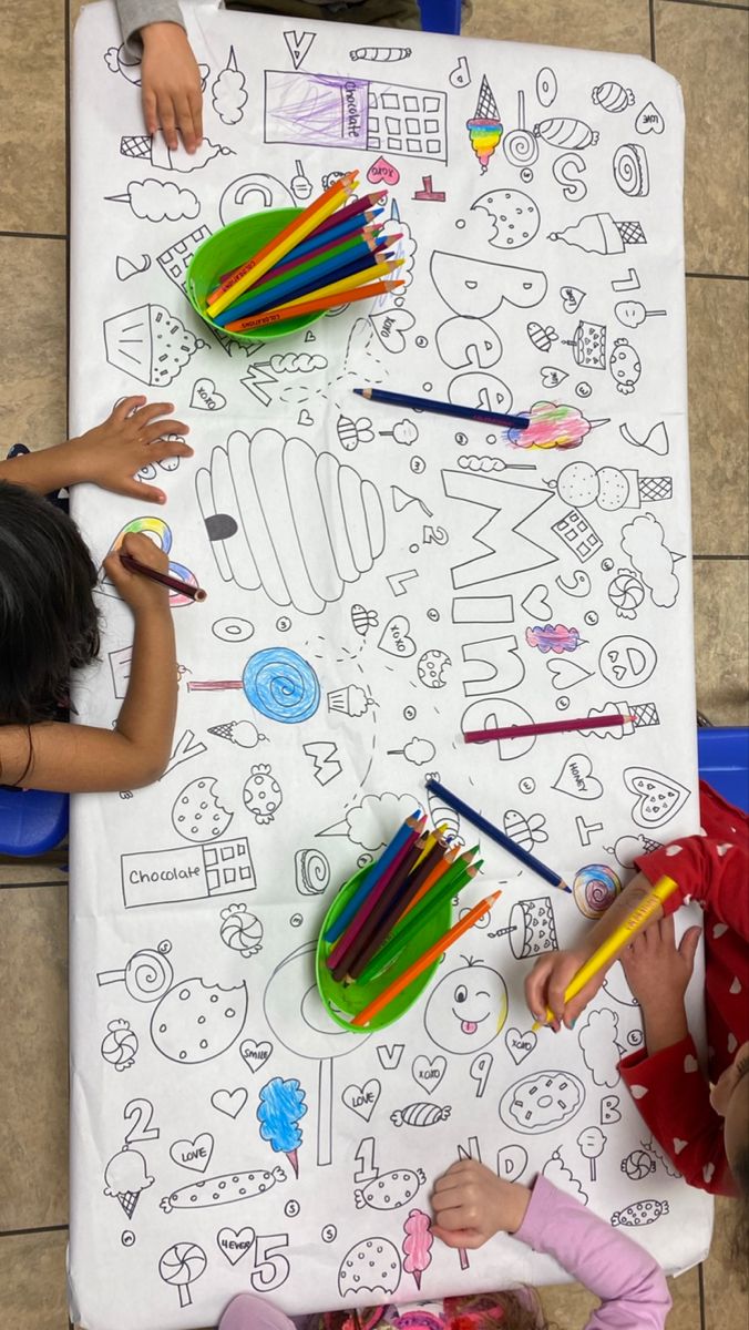 two children are sitting at a table with colored pencils and crayons on it