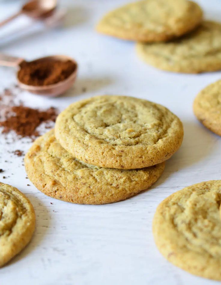 chocolate chip cookies are arranged on a baking sheet with cocoa powder and spoons in the background