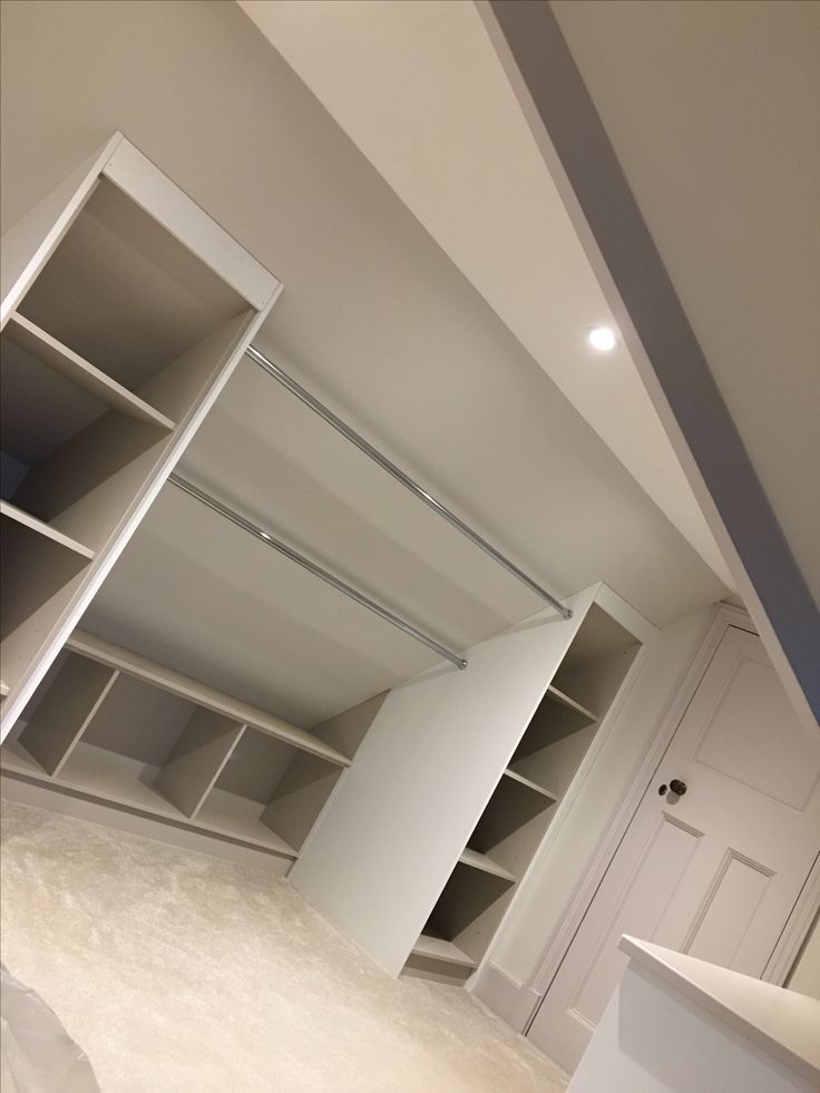 an empty closet with white walls and shelving in the middle is seen from across the room