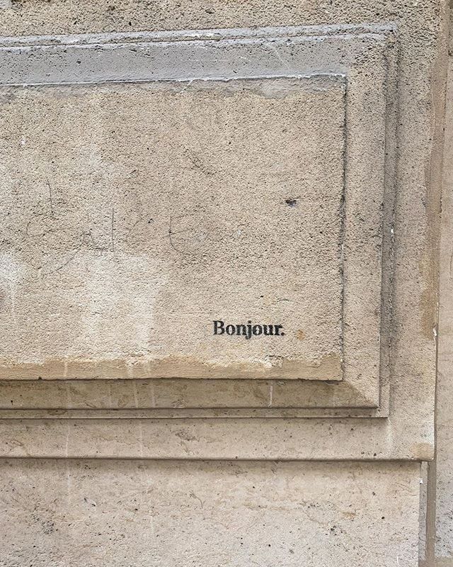 the word bonjou written in black ink on a stone wall with an inscription below it