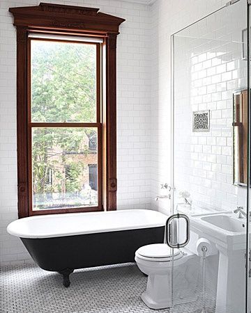 a white and black bath tub sitting next to a toilet in a bathroom under a window