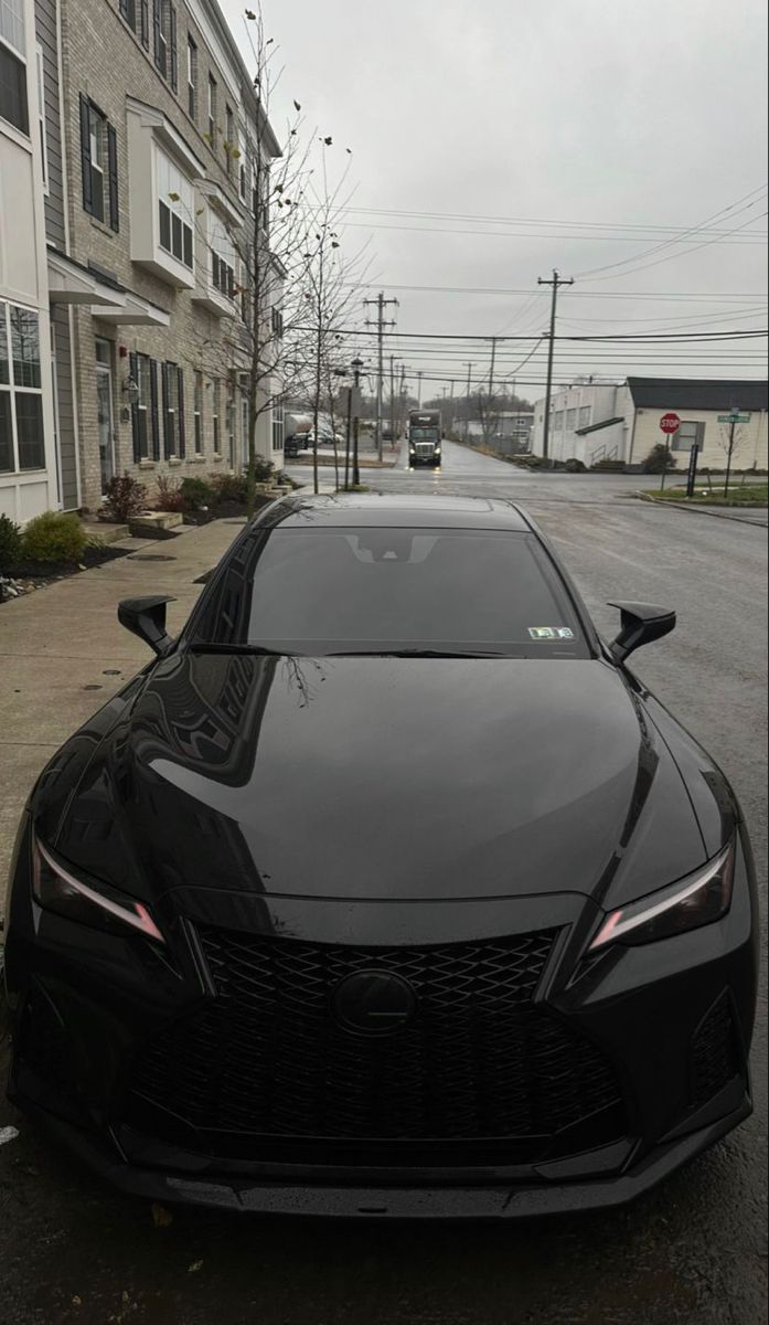 a black sports car is parked on the side of the road in front of an apartment building