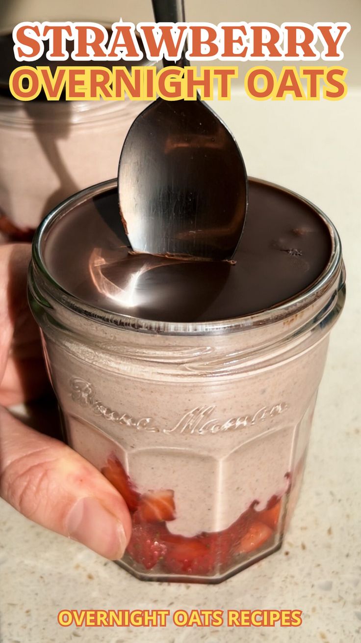 a person holding a spoon in a jar filled with overnight oats