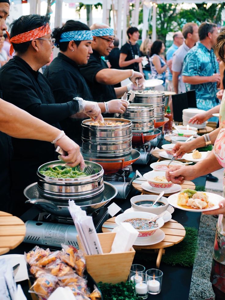 a group of people standing around a buffet table with food on it's plates