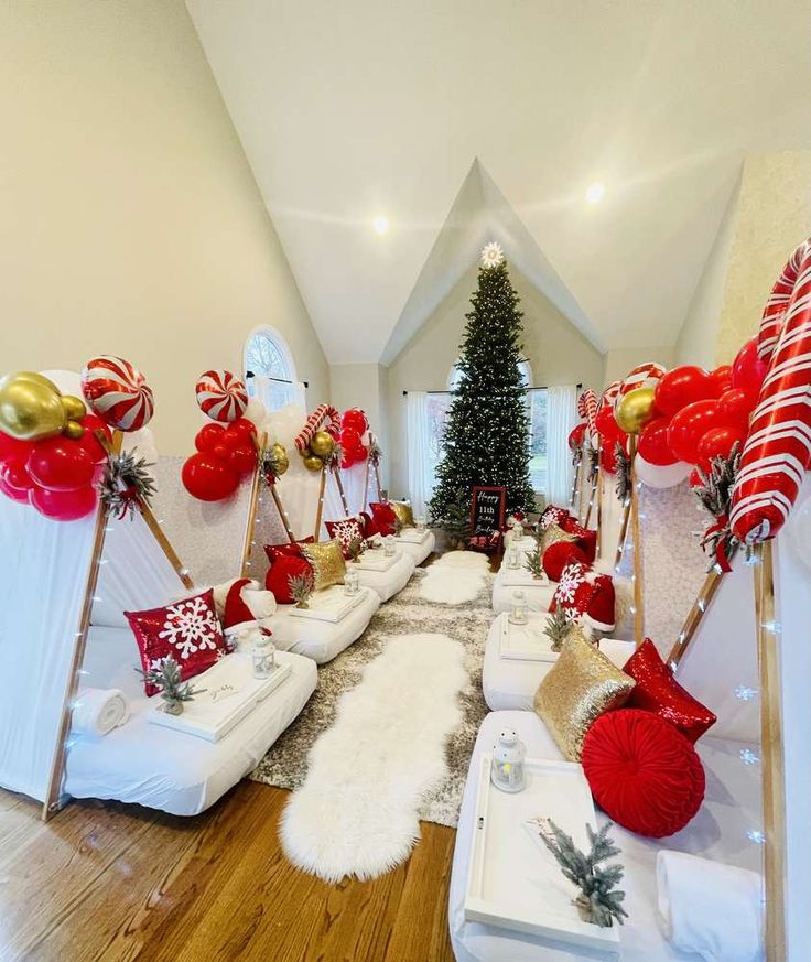 a room decorated for christmas with white couches and red and gold decorations on the walls