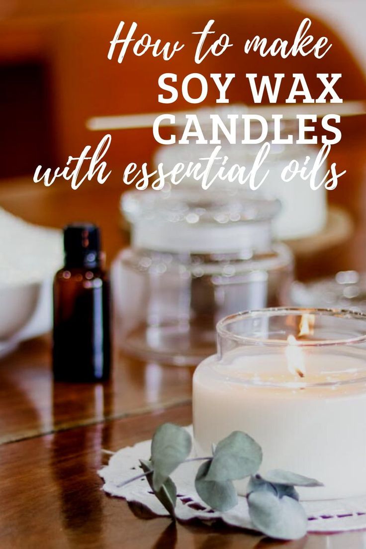 a candle sitting on top of a wooden table next to a bottle of essential oils