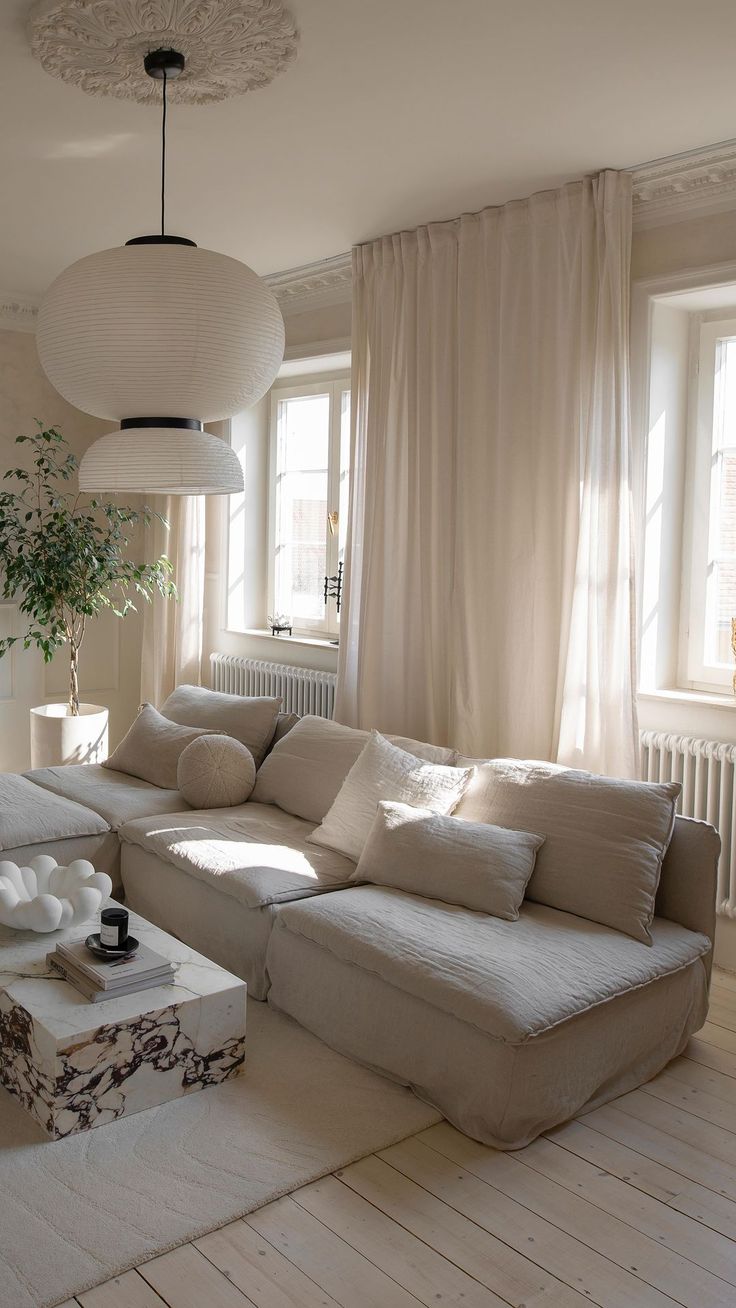 a living room filled with furniture and a large white couch in front of two windows