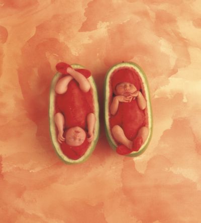 two babies are sleeping inside the pod of a watermelon, which is cut in half and placed next to each other