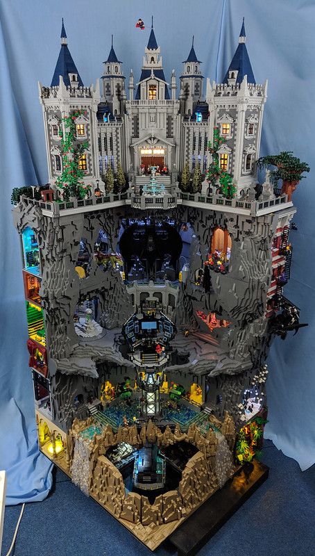 a large lego castle with lots of windows and lights on it's sides is shown in front of a blue backdrop