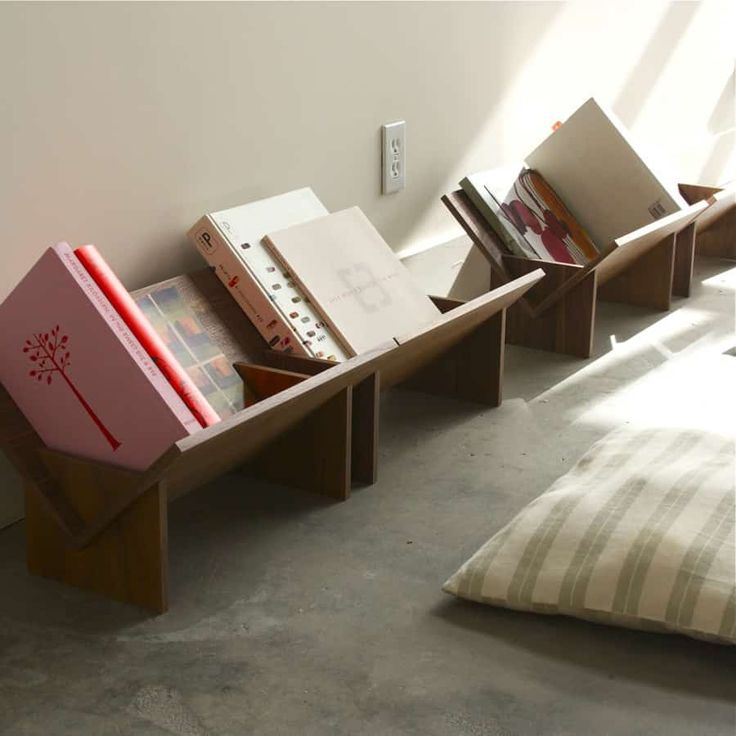 three books are stacked on top of each other in the corner of a room with sunlight coming through the window