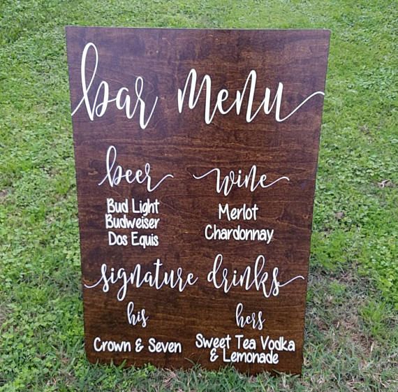 a wooden sign sitting on top of a grass covered field next to a lush green field