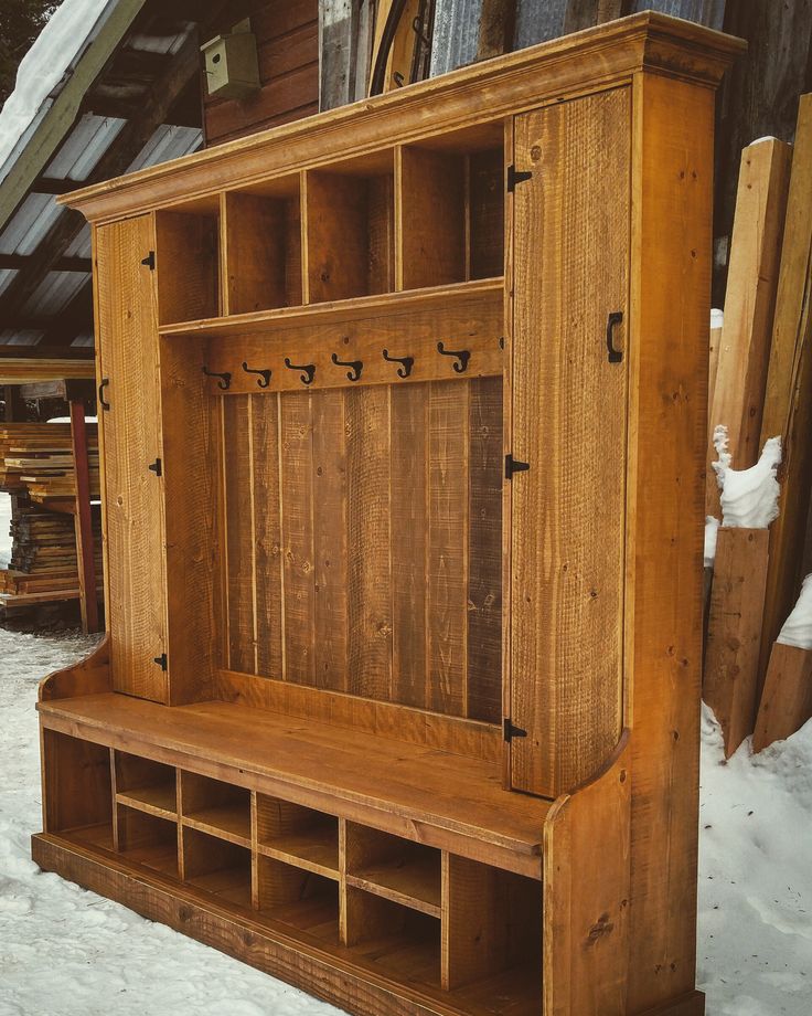 an old wooden shelf with hooks on it in the snow