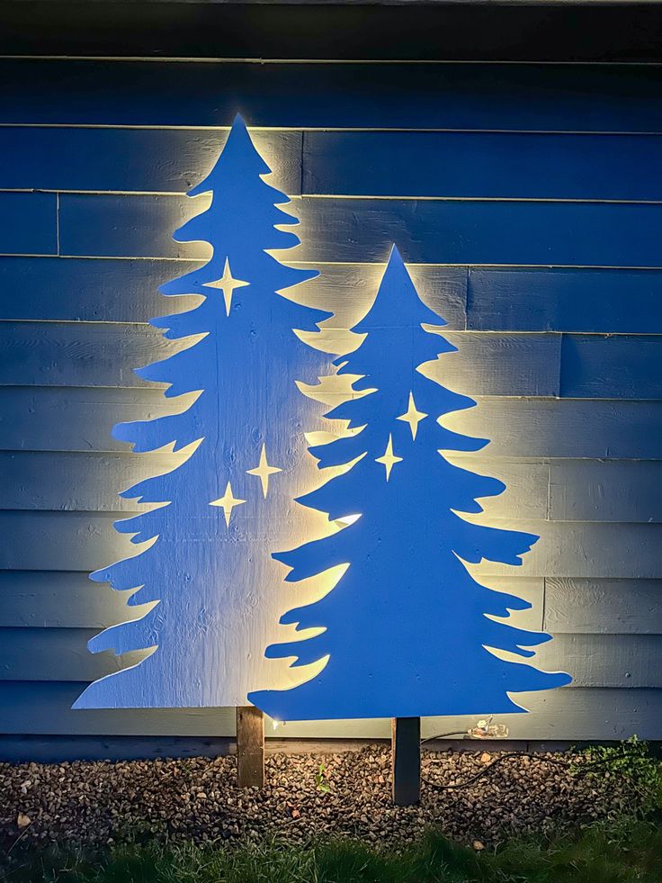 a lit up christmas tree sitting in front of a blue building with stars on it