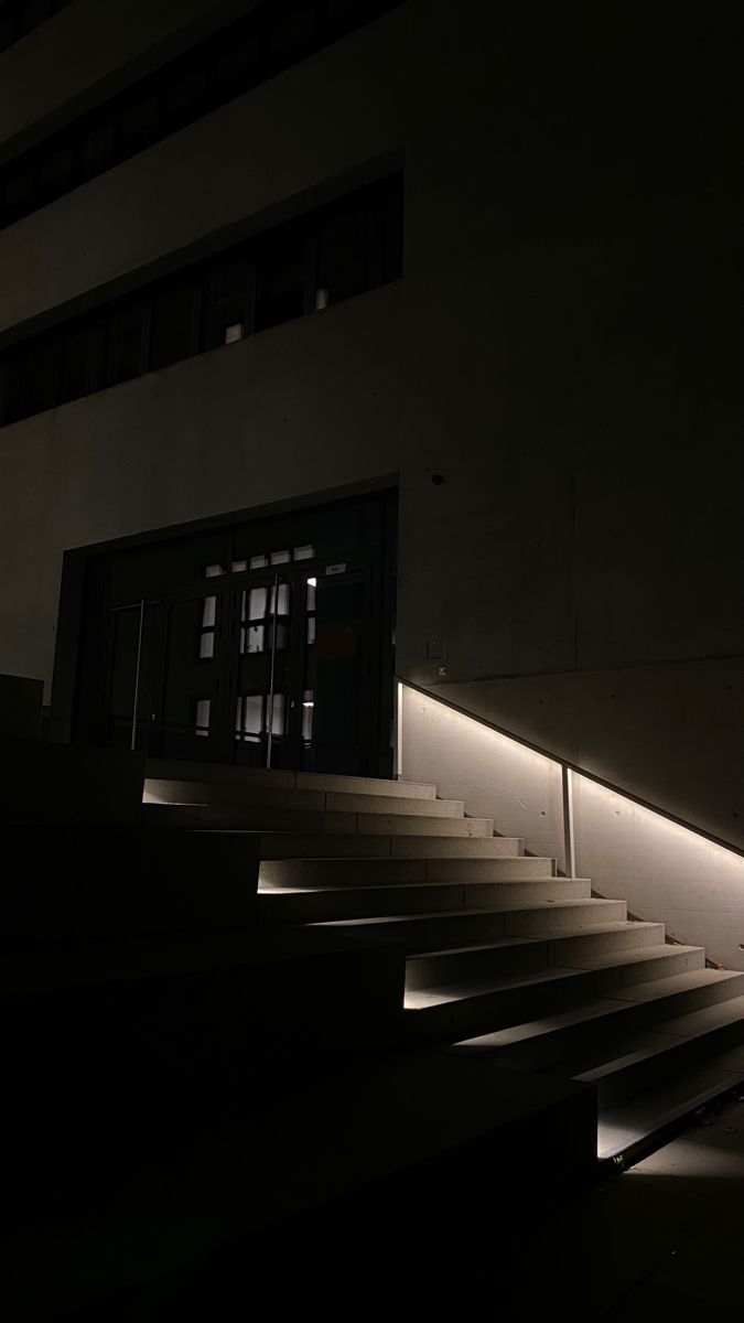 stairs lit up at night in front of a building with light coming from the windows