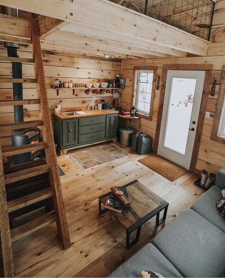 a living room filled with furniture next to a kitchen and dining area in a log cabin