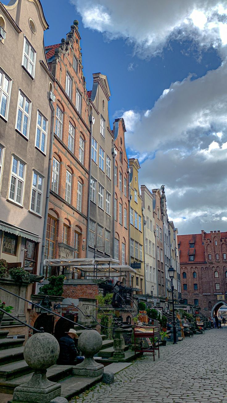 a cobblestone street lined with tall buildings and stone steps leading up to them