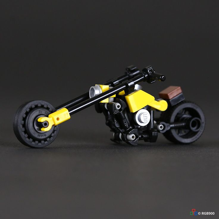 a yellow and black toy motorcycle sitting on top of a gray floor next to a wall