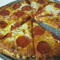 a pepperoni pizza cut into slices with a knife