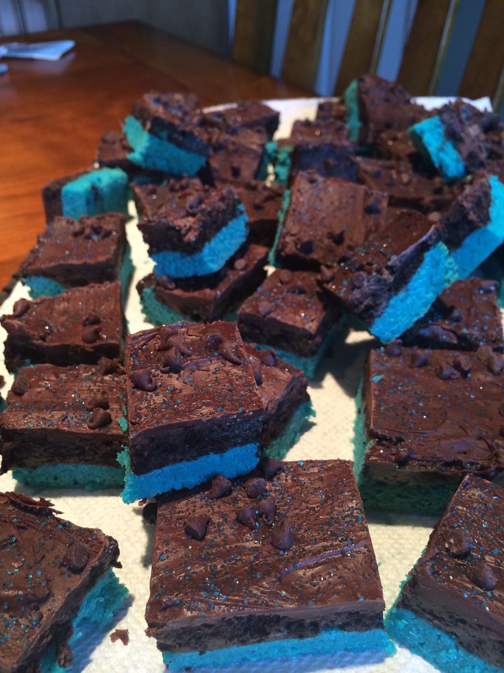 there are many brownies with blue frosting on the table and one is cut in half