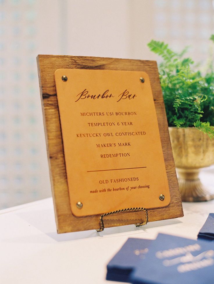 a wooden sign sitting on top of a table next to a vase filled with flowers