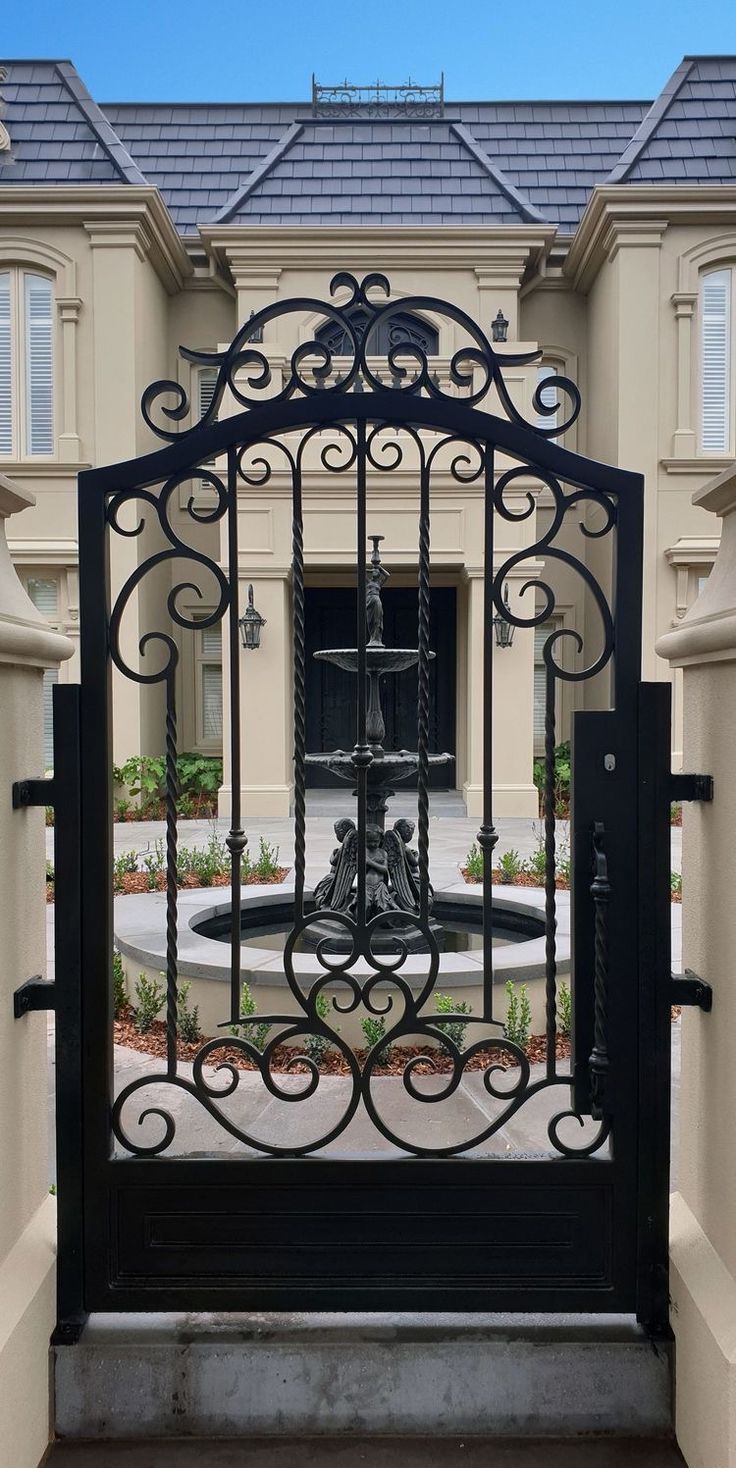 an iron gate in front of a large house