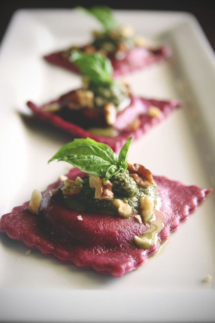 three small pieces of food on a white plate with green leafy garnish