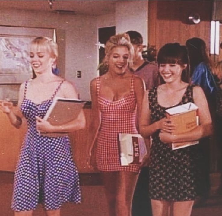 three women standing next to each other holding books