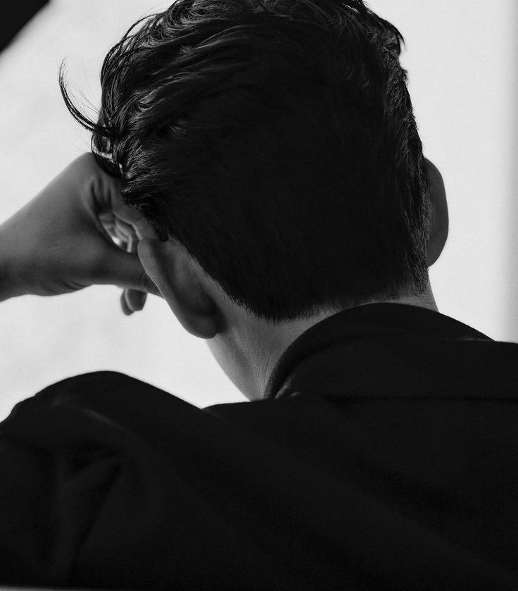 black and white photograph of a man with his hand on his head looking off into the distance