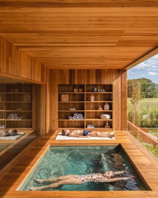 an indoor swimming pool in the middle of a wooden building with shelves on each side