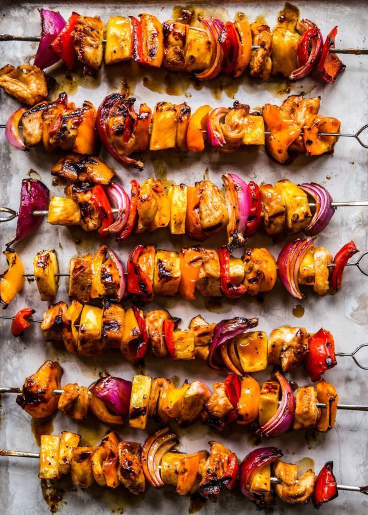 several skewers filled with meat and vegetables on a sheet of baking trays