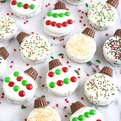 frosted cupcakes decorated like snowmen on a white table with sprinkles