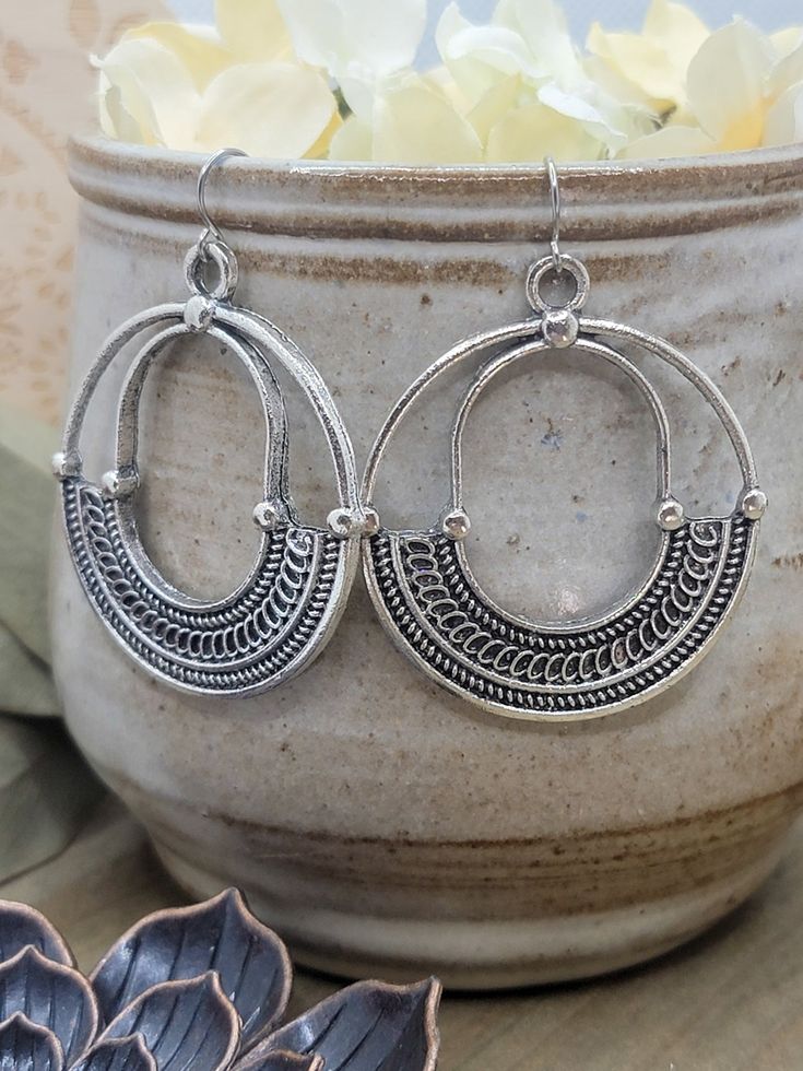 Grab attention with these chic, 2.5" Bohemian hoops! The antique silver tribal pendants will enhance any outfit.. Plus, they're hypoallergenic, so you can rock these statement earrings worry free. Antique Silver plate Bohemian hoops Stainless steel ear hooks Hypoallergenic Measure 2.5" Created in studio - Wilmington, NC Cheap Bohemian Silver Hoop Earrings, Antique Silver Bohemian Earrings, Bohemian Metal Dangle Hoop Earrings, Bohemian Metal Hoop Earrings, Bohemian Metal Hanging Hoop Earrings, Small Metal Hoop Earrings In Bohemian Style, Bohemian Hoop Earrings With Oxidized Finish, Nickel Free Metal Hoop Earrings For Festivals, Silver Bohemian Hoop Earrings With Oxidized Finish