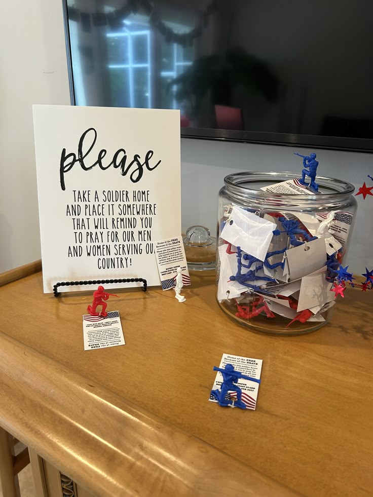 a glass jar filled with red, white and blue confetti next to a sign that says please