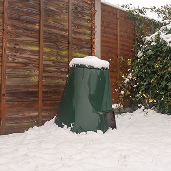 a fire hydrant covered in snow next to a fence and shrubbery on a snowy day