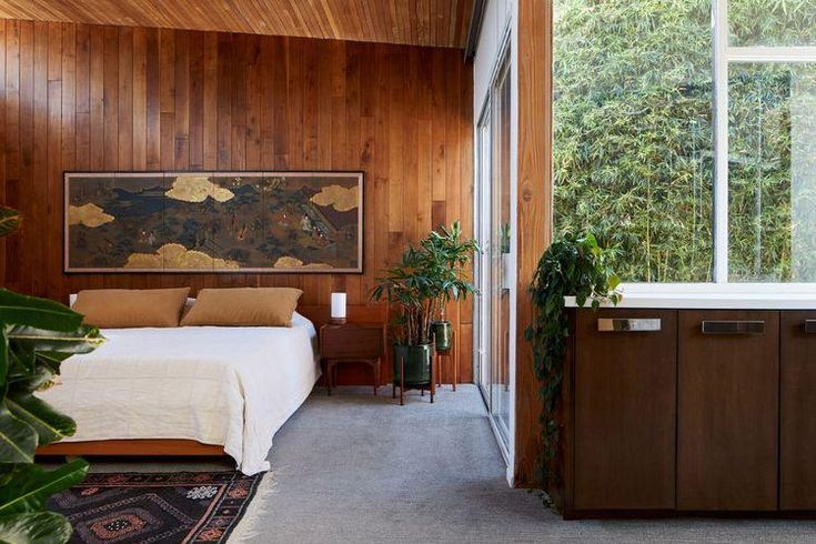 a bedroom with wood paneling and a large painting on the wall next to a bed