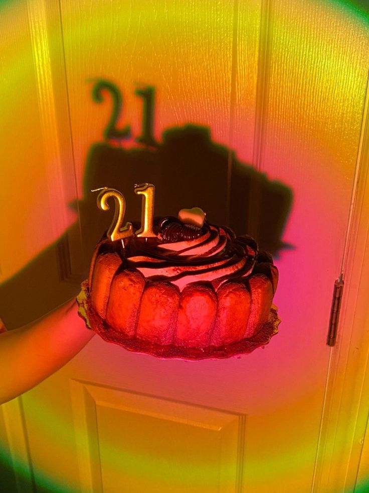 a person holding a cake in front of a door with the number 12 on it