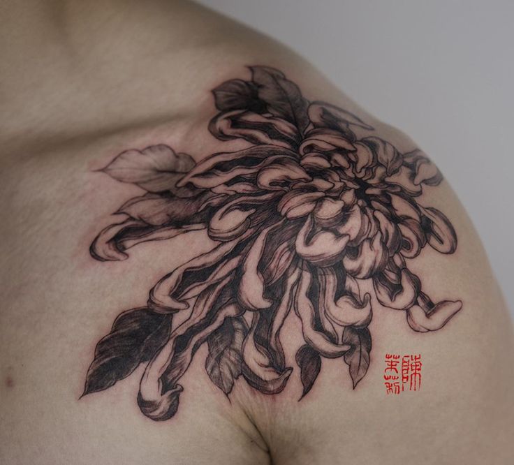 a close up of a person's chest with flowers on it and chinese writing