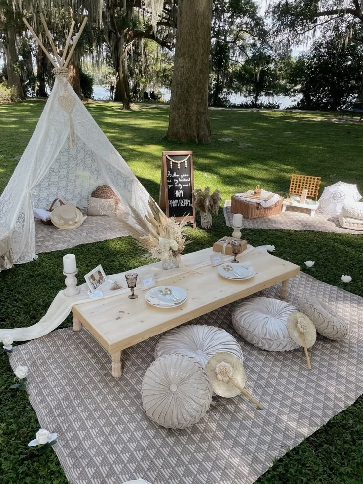 a picnic table with umbrellas and plates on it in front of a teepee tent