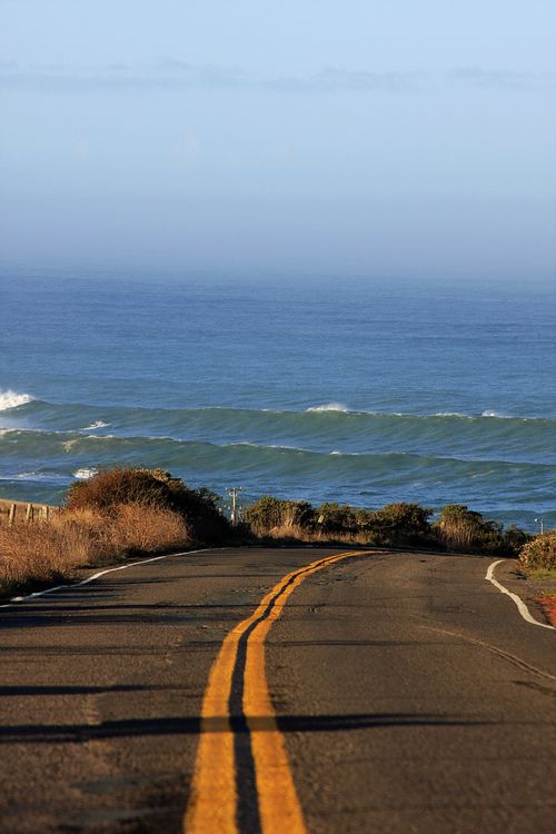 an empty road with the ocean in the background