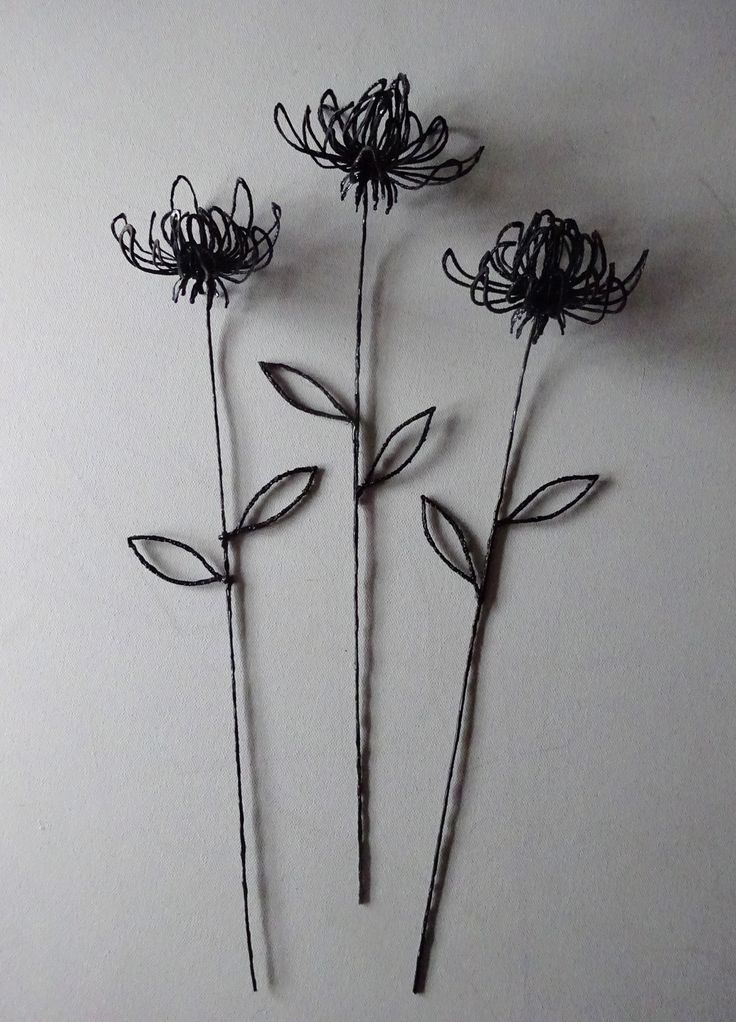 three metal flowers on a white surface with one flower bud still attached to the stems