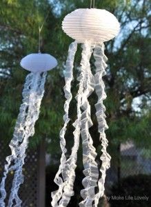 two white paper lanterns hanging from strings in the shape of jellyfishs and other sea creatures