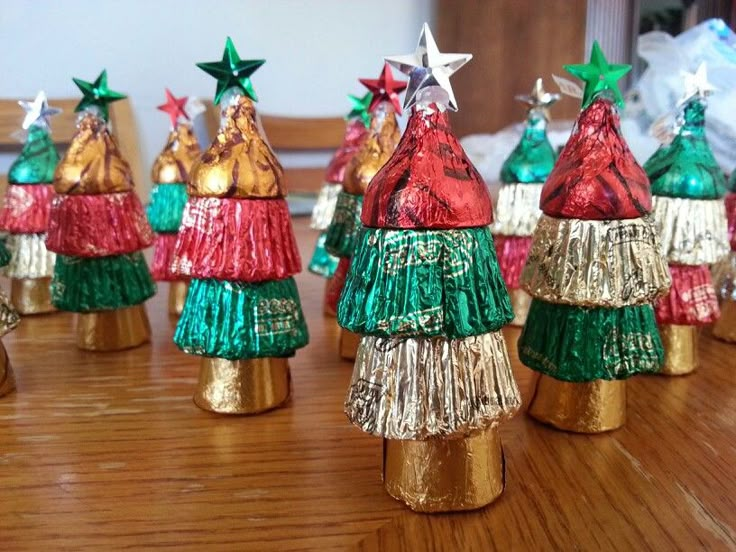 small christmas trees made from tinsel wrapped in gold and green foil on a wooden table