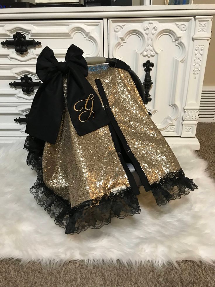 a gold sequin skirt with a black bow on the front, and a monogrammed ribbon around the waist