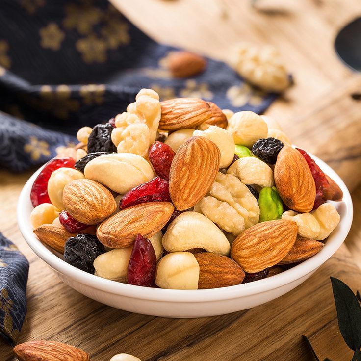 a bowl filled with nuts and raisins on top of a wooden table