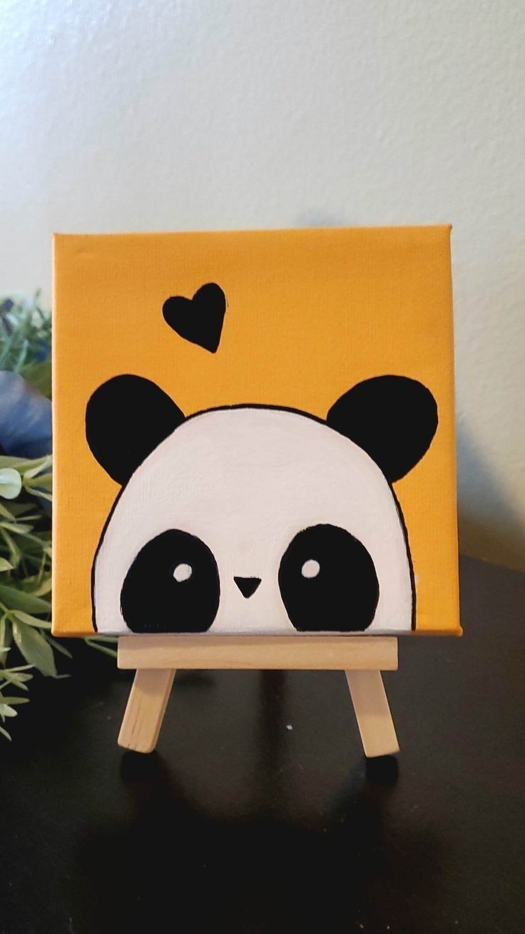 a small wooden easel with a painting of a panda bear on it's face