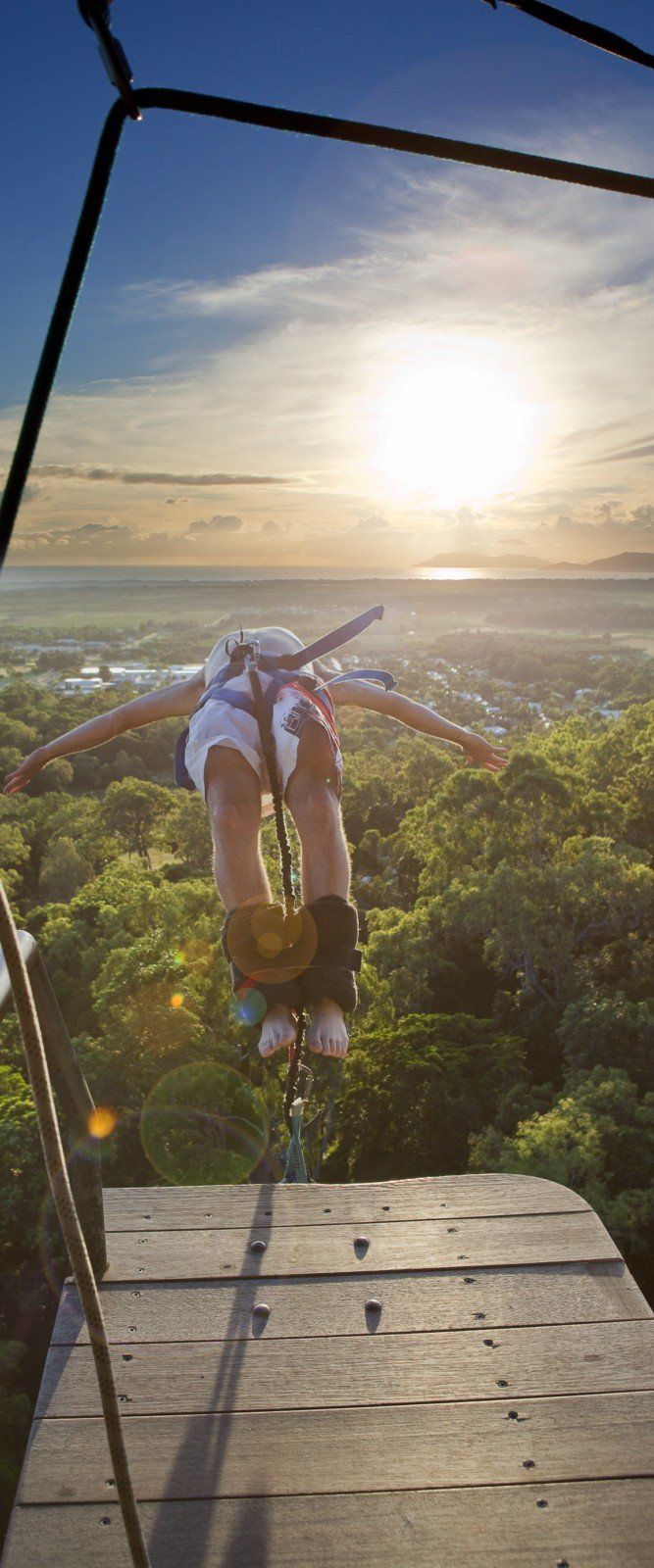 the man is doing tricks on his bike in the air over the trees and water