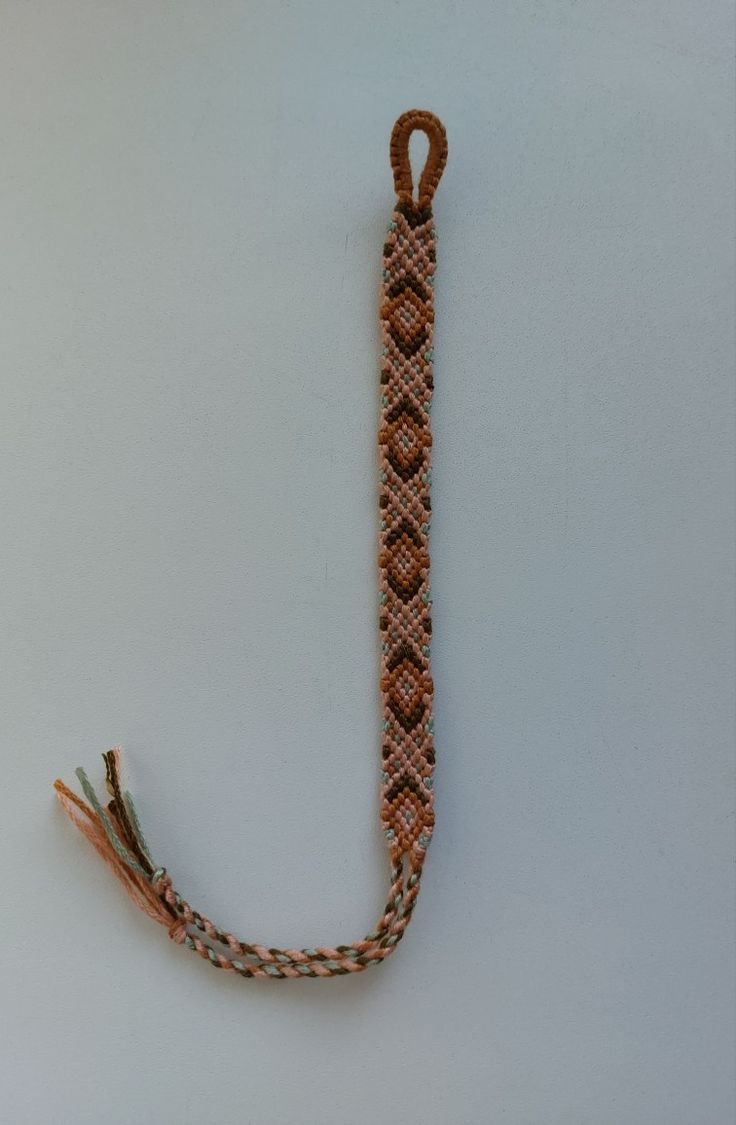 an orange and white beaded lanyard attached to a hook on a wall or floor