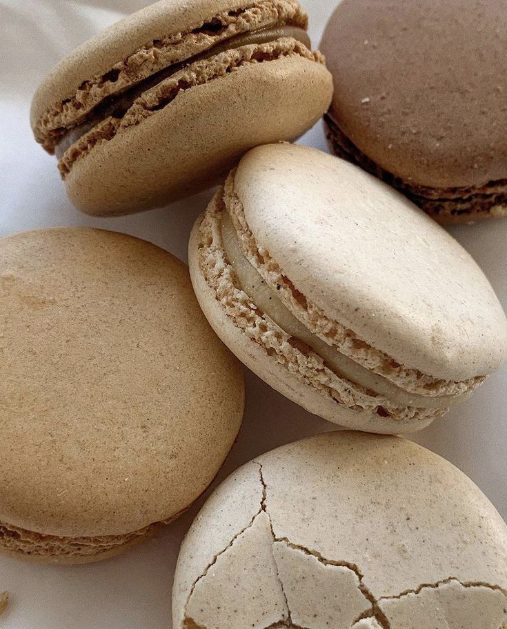 three macaroons are sitting next to each other on a white tablecloth with holes in it