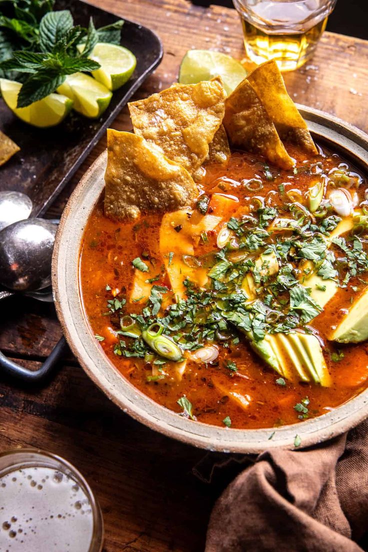 a bowl of soup with tortilla chips and avocado on the side